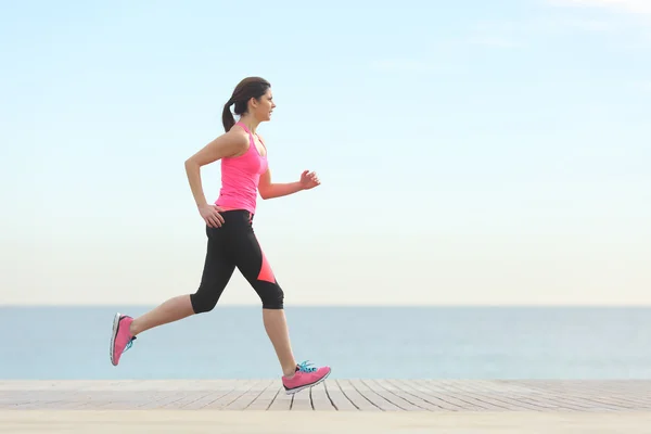 Vista lateral de una mujer corriendo por la playa —  Fotos de Stock