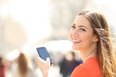 Mutlu kadın bir smartphone kullanarak sokakta yürürken