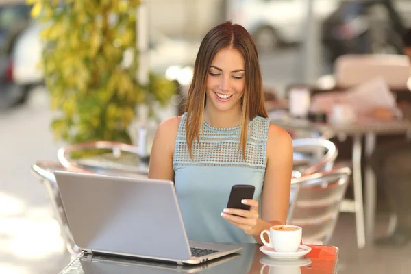 Entreprenör som arbetar med en telefon och laptop i ett kafé — Stockfoto