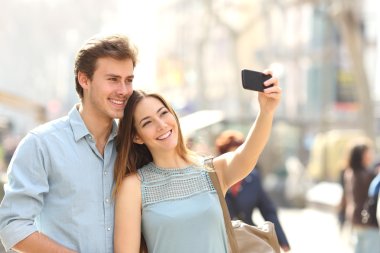 Couple of tourists photographing a selfie in a city street clipart