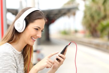 Genç kız bir tren bekleyen kulaklık ile müzik