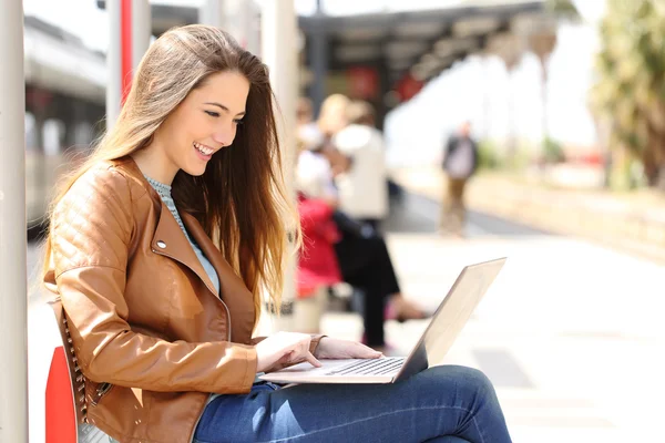 Ragazza che utilizza un computer portatile in attesa in una stazione ferroviaria — Foto Stock