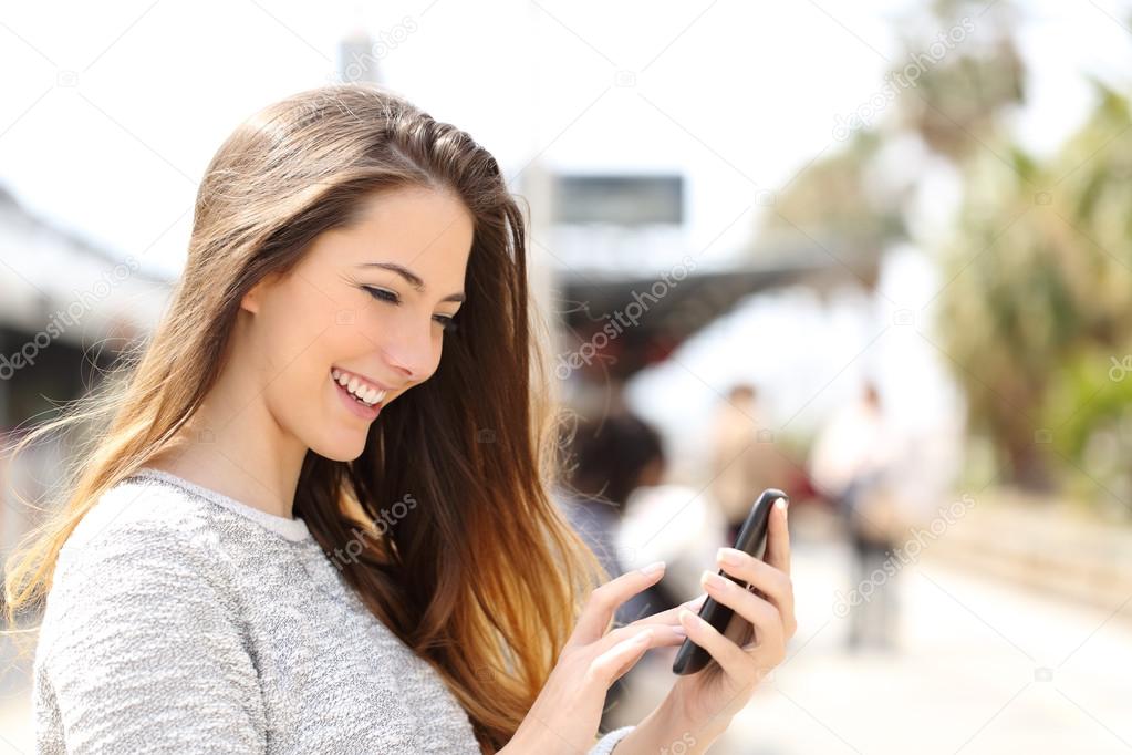 Girl texting on a smart phone in a train station