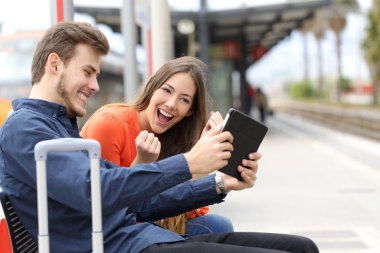 Mutlu çift bir tren istasyonunda bir Tablet oyun oynamak