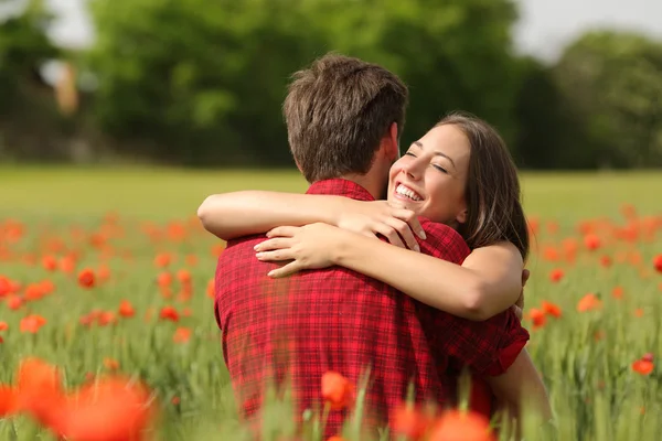 Paar umarmt sich nach Heiratsantrag in einem Blumenfeld — Stockfoto