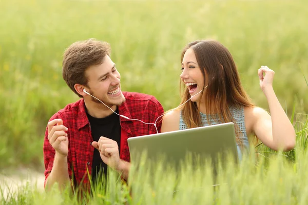 Pareja cantando y escuchando música desde un portátil — Foto de Stock