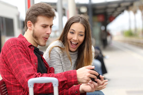 Пара грає в ігри зі смартфоном на залізничній станції Стокова Картинка