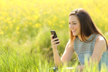 Yeşil alana bir akıllı telefon kullanan kadın