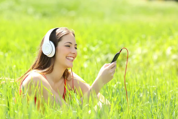 Kız bir alanda akıllı telefon ve kulaklık ile müzik dinleme — Stok fotoğraf