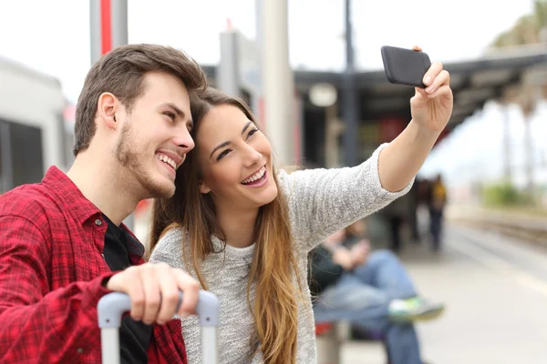 Casal de viajantes fotografando uma selfie com um smartphone — Fotografia de Stock