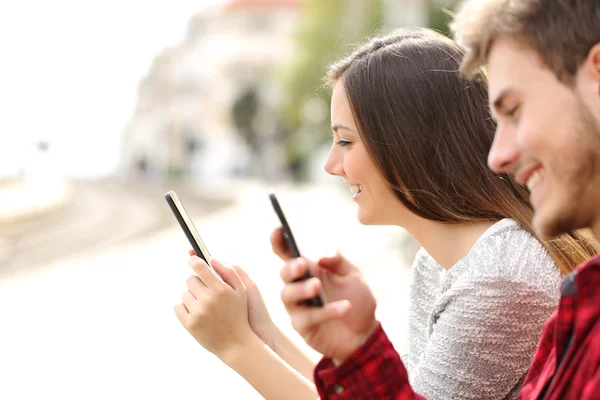 Tiener paar met behulp van slimme telefoons in een treinstation — Stockfoto