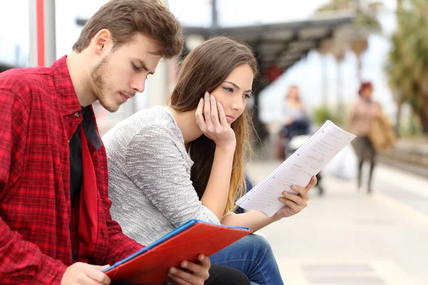 Deux étudiants étudient le transport en attente dans une gare — Photo