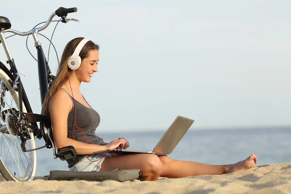 Teen girl studying with a laptop on the beach — Stockfoto