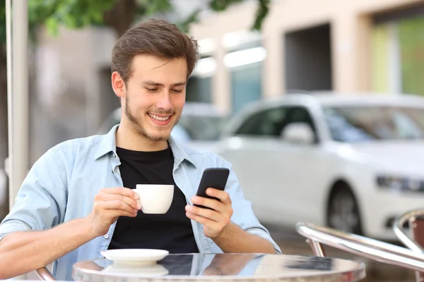 Homem usando um telefone inteligente em uma cafeteria — Fotografia de Stock