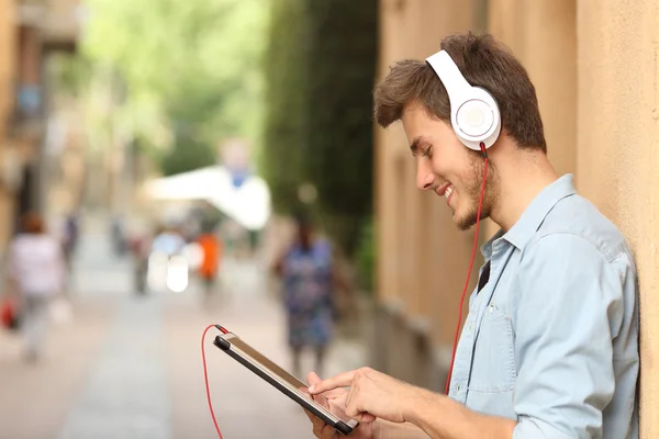 Man using a tablet with headphones on the street — Stockfoto