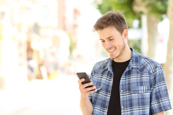 Молодой случайный человек, использующий смартфон на улице — стоковое фото