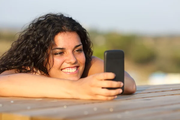 Grappig meisje kijken van de media in slimme telefoon — Stockfoto