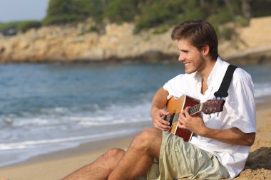 Yakışıklı adam sahilde klasik gitar çalmak