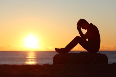 Sad man silhouette worried on the beach clipart