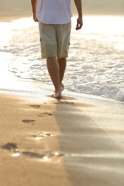 Achteraanzicht van de benen van een man lopen op het strand — Stockfoto