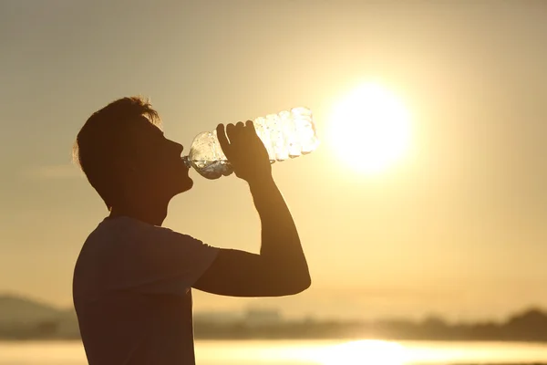 Fitness man silhouet drinking water uit een fles — Stockfoto