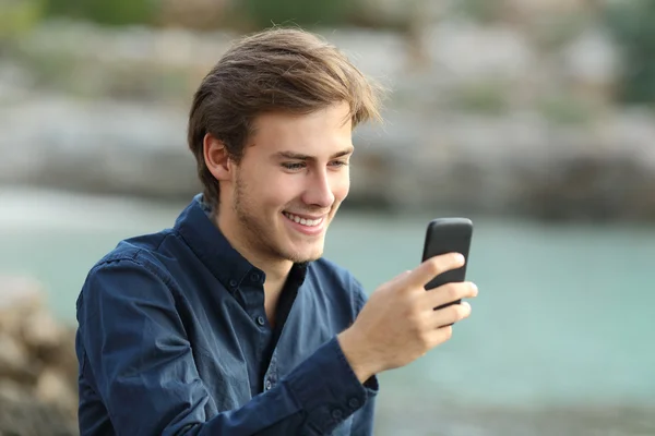 Mann, der am Strand am Telefon SMS schreibt — Stockfoto