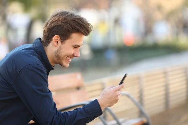 Cara feliz usando um telefone inteligente em um parque — Fotografia de Stock