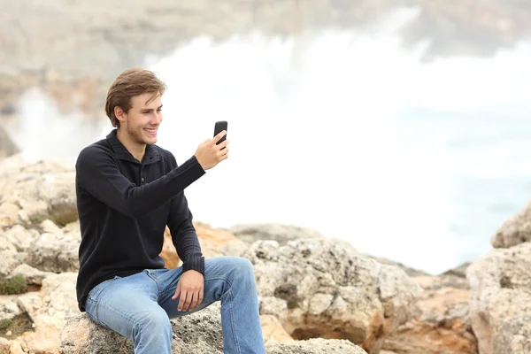 Man using a smart phone in winter on the beach — 스톡 사진