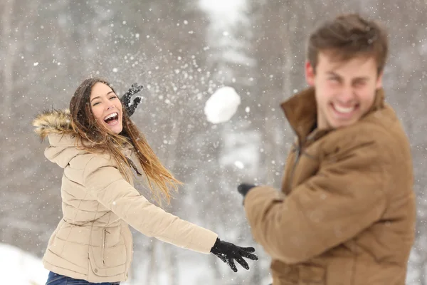 Couple jouant avec la neige et petite amie lançant une balle Photo De Stock