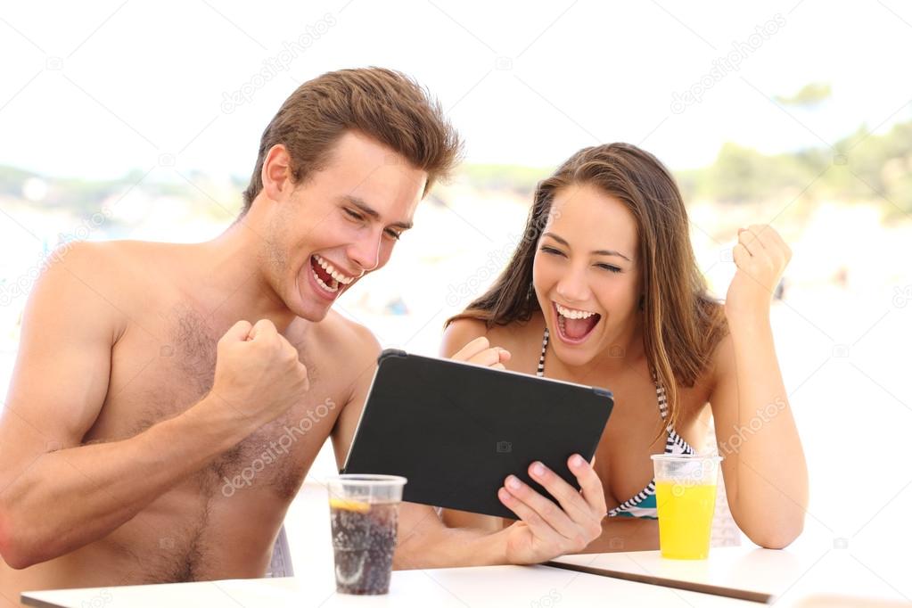 Euphoric couple of winners watching a tablet