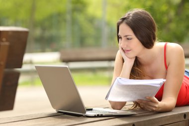 Bir üniversite kampüsü içinde bir laptop ile okuyan öğrenci kız