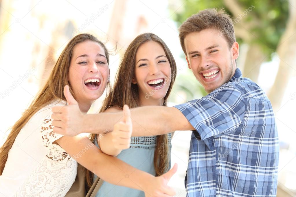 Three happy teenagers laughing with thumbs up