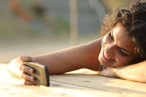 Девушка смотрит видео или социальные сети в смартфоне — стоковое фото