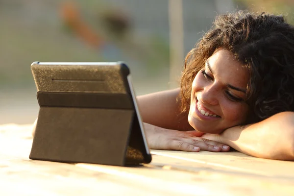 Mujer viendo vídeos en una tableta al atardecer — Foto de Stock