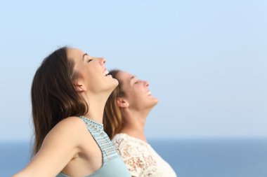 Two girls breathing deep fresh air on the beach clipart