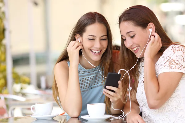 Venner deler og lytter til musik med smartphone - Stock-foto