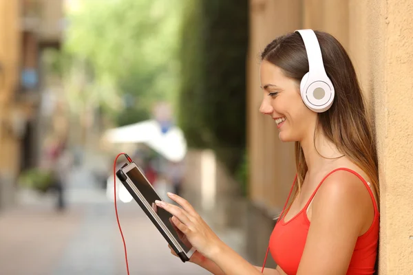Girl browsing a tablet and listening with headphones — Stok fotoğraf
