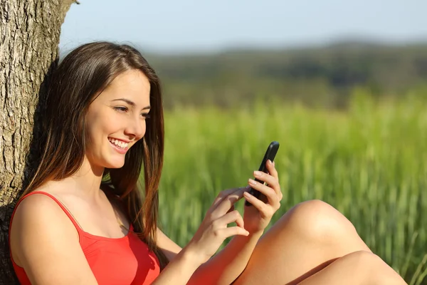 Menina mensagens de texto em um telefone inteligente relaxado no país — Fotografia de Stock