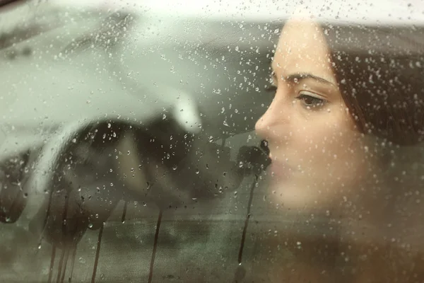 Sad woman looking through a car window — ストック写真