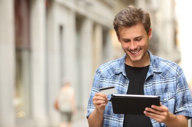 Man buying online with a credit card and a tablet clipart