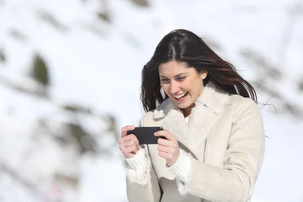 Woman playing games in a smart phone on winter holidays — Stock Photo, Image