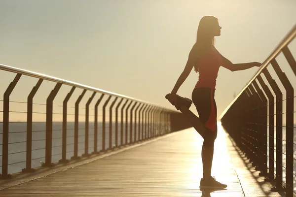 Woman silhouette exercising stretching on a bridge — Stock Photo, Image