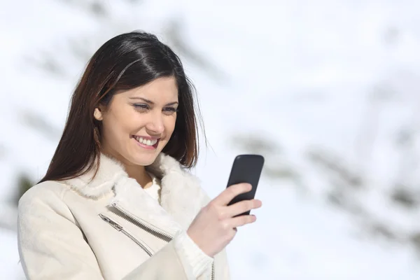 Mujer usando un teléfono inteligente en vacaciones de invierno — Foto de Stock