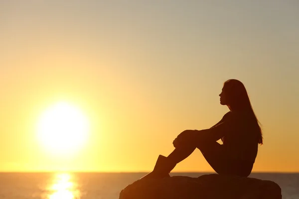 Silhouet van de vrouw kijken naar de zon in een zonsondergang Stockfoto