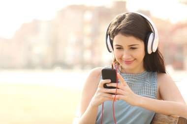 Kız akıllı telefon kulaklık ile müzik dinleme