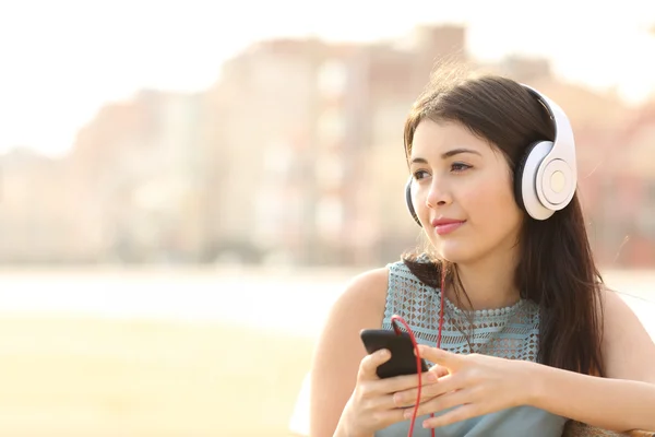 Chica cándida escuchando música con un teléfono inteligente — Foto de Stock