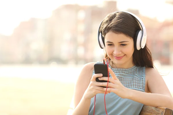 Κορίτσι ακούγοντας μουσική με ακουστικά από ένα έξυπνο τηλέφωνο — Φωτογραφία Αρχείου