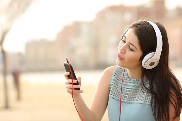 Menina adolescente cantando e ouvindo música de um telefone inteligente — Fotografia de Stock