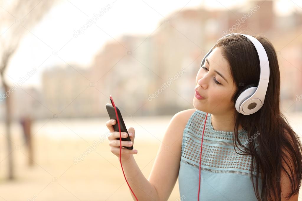 Teen girl singing and listening music from a smart phone
