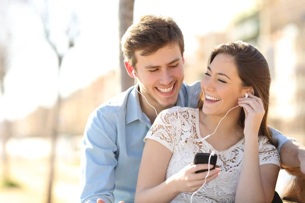 Par lyssnar på musik från en smart telefon — Stockfoto
